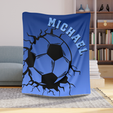 Blue throw blanket with image of a soccer ball breaking through with cracks around it. The name Michael in lighter blue arched over the top. 