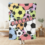 Throw blanket covered in bright colored soccer balls, with the name Hannah going through the center in a pink varsity font. 
