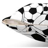 A close-up of a square throw pillow with a black and white soccer ball pattern, shown with its zipper partially open to reveal a light beige interior.