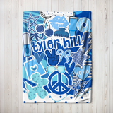 A throw blanket in shades of blue featuring pop culture graphics like lip prints, sunglasses, peace signs, and the camp name 'Tyler Hill'.