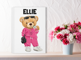 a white journal with a teddy bear on it, wearing a hot pink track suit, drinking an iced drink and holding a black purse. The name Ellie in black at the top. 