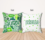 A square decorative throw pillow with greens and white graphic collage featuring the camp 'laurel' in large blue letters, hearts, stars, and candy illustrations. The back of the pillow is white with green polka dots and the name 'Brielle' across the center in green.