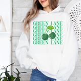 A woman wearing a white pullover hoodie with a green graphic print on the front. The print features the words 'GREEN LANE' repeated vertically in green, overlaid with a graphic of two green cherries with a single green leaf.