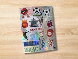 A rectangular sticker sheet featuring various sports-themed stickers including basketball, soccer, football, baseball, and stars, with the text 'GAME DAY' and 'ISAAC', displayed on a light wood background.
