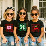 Three girls sitting on a porch swing wearing matching black graphic t-shirts with 'PONTIAC' and 'TACONIC' text and different designs: pink lips, green bow, and red cherries, paired with ripped blue jeans and black sunglasses.