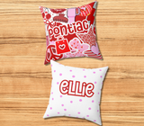 A square decorative throw pillow with red and pinks and white graphic collage featuring the camp 'pontiac' in large red letters, hearts, stars, and candy illustrations. The back of the pillow is white with red polka dots and the name 'Ellie' across the center in red.