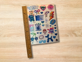 A sheet of colorful hand-drawn stickers with various doodles, hearts, and text like 'DAISY' and 'CAMP' placed next to a wooden ruler on a light wood grain surface.