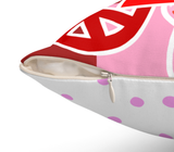 Close-up of a square throw pillow with a colorful geometric print featuring red, pink, and white shapes, with a white bottom section decorated with pink polka dots. The pillow is shown open to reveal the cream-colored fabric lining and a silver zipper pull.
