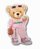 A pillow in the shape of a cartoon teddy bear wearing sunglasses, a pink sweatsuit with "TACONIC" and it's zip code printed on it, and pink sneakers. The bear is holding a drink and a brown purse.