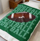 Green blanket with 'FOOTBALL' on repeat going down the whole blanket, a big football in the center with the name 'GABE' on the ball in white. 