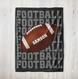 Black blanket with 'FOOTBALL' on repeat going down the whole blanket, a big football in the center with the name 'SAMSON' on the ball in white. 