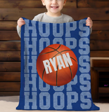 blue throw blanket with 'HOOPS' going down the whole blanket on repeat. a big basketball in the center with a name in white going through it. 