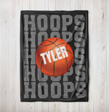 black throw blanket with 'HOOPS' going down the whole blanket on repeat. a big basketball in the center with a name in white going through it. 