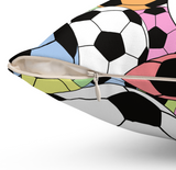 Close-up of a decorative throw pillow with a colorful soccer ball pattern, showing a partially unzipped front pocket with a cream zipper pull.