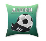 A square decorative throw pillow with a green gradient background, featuring the name 'AIDEN' in white varsity-style letters above a soccer ball and a black soccer cleat.