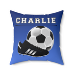 A square blue throw pillow featuring a custom design with the name 'CHARLIE' in white varsity letters, a black and white soccer ball, and a black cleat with white stripes.
