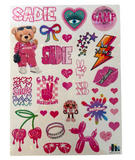 A sheet of colorful die-cut stickers featuring various designs including a teddy bear, hearts, bows, stars, a balloon dog, cherries, and text like 'SADIE', 'CAMP WESTMONT', and 'live 10 for 2' on a white background.