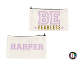 White canvas case with the text 'BE FEARLESS' in lavender and gold glitter on the front and the name 'harper' on the back. 